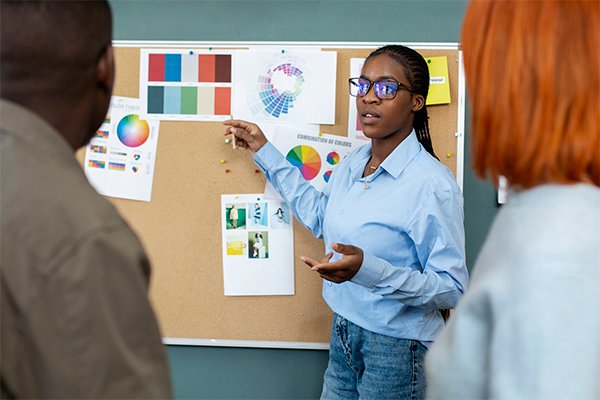 A female student explaining the project scope to fellow students whilst pointing on the workboard