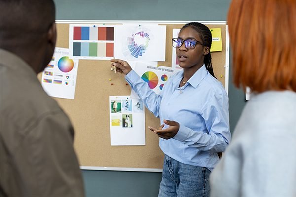 A female student explaining the project scope to fellow students whilst pointing on the workboard